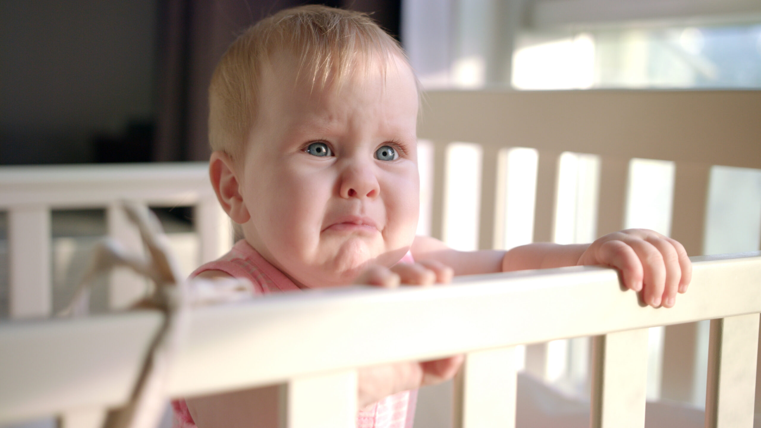 baby standing and crying in cot