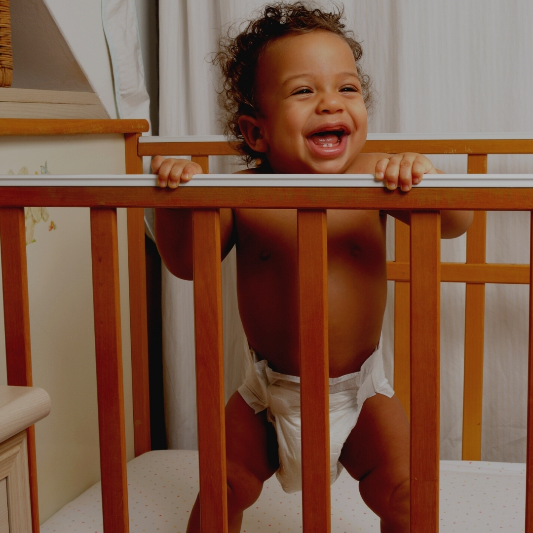 baby standing in cot and laughing